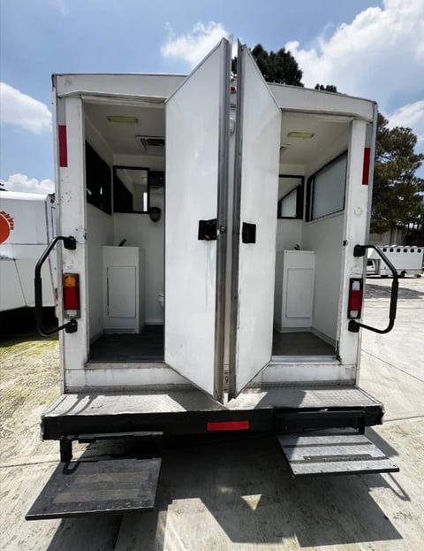 White enclosed cargo trailer with open double doors showing interior compartments and metal loading steps