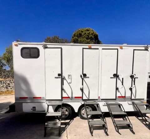 White horse trailer with multiple compartments and ramps extended on a sunny day