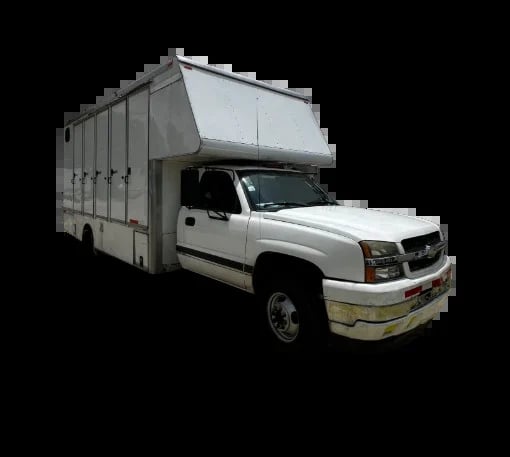 White pickup truck with large gray enclosed cargo box mounted on bed, photographed against black background