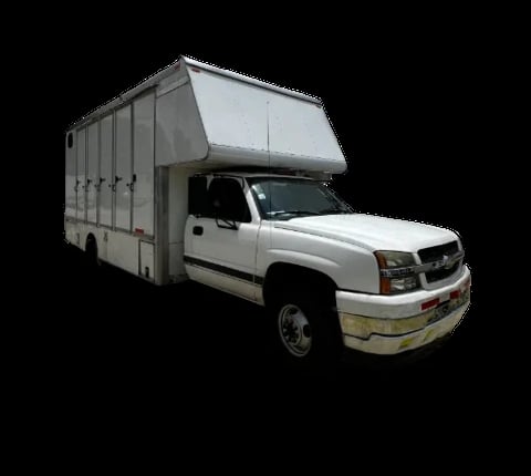 White pickup truck with large gray enclosed cargo box mounted on bed, photographed against black background