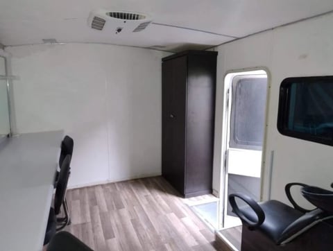 Interior of a white enclosed trailer with wood-like flooring, black storage cabinet, and partial view of equipment on the sides