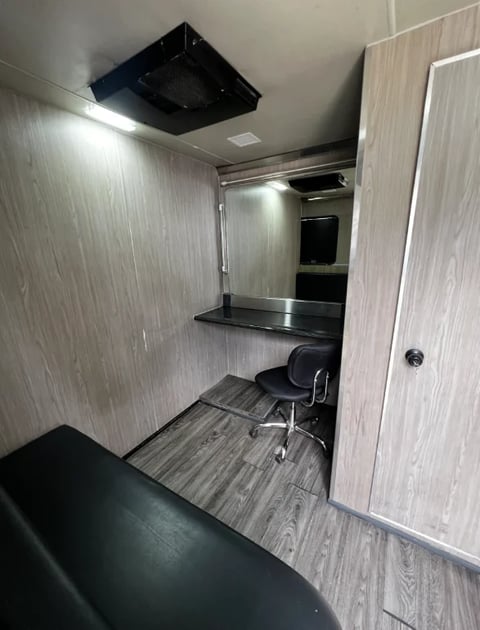 Interior of a mobile office pod with desk, chair, LED lighting, and wood-grain walls