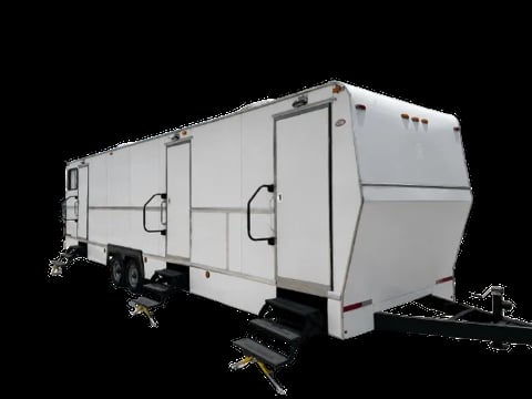 White travel trailer with dual entry doors and hitch, isolated against black background
