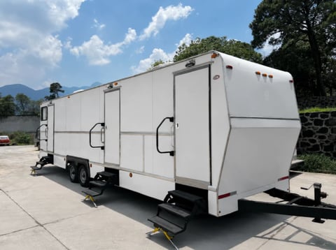White enclosed cargo trailer parked on a concrete surface with mountains and trees in the background