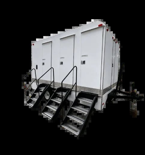 White portable restroom trailer with three stalls, black metal stairs, and wheels on black background