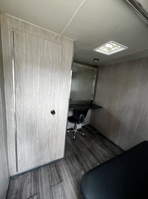 Interior view of a modern office space with light wood door, desk with black chair, and vinyl flooring under LED ceiling light